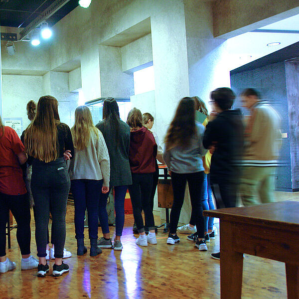 Eine Gruppe Jugendlicher schaut einer Vorführung zu.