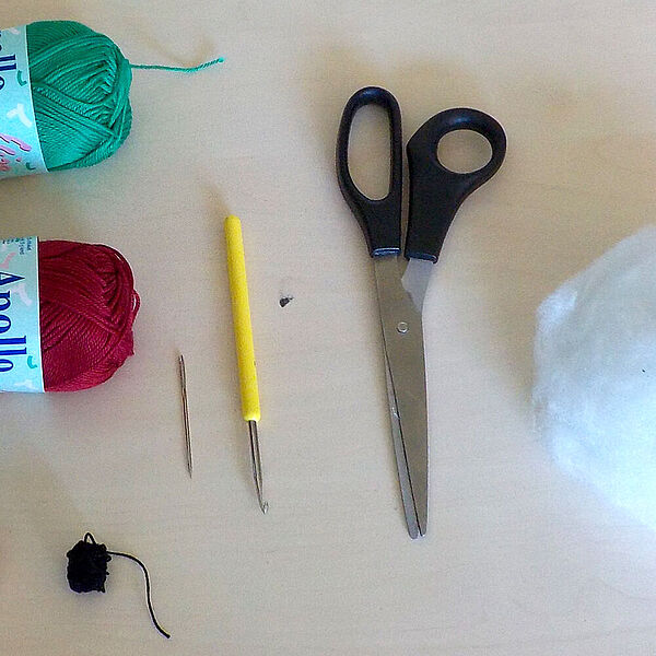 Utensilien zum Häkeln liegen auf einem Tisch