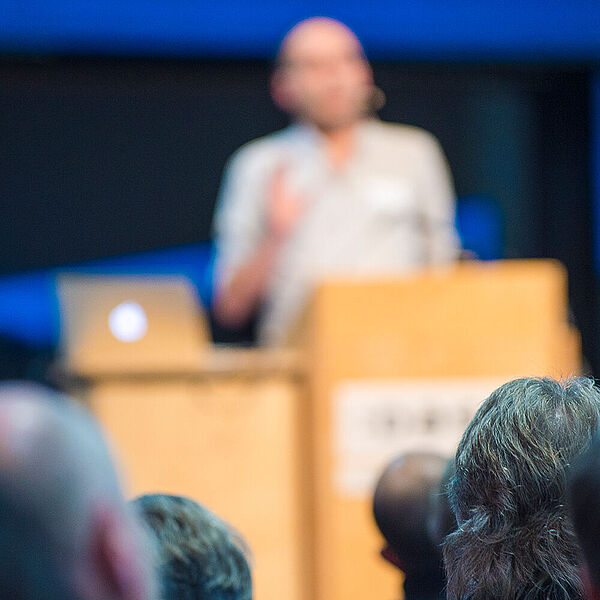 Ein Mann steht am Rednerpult und spricht auf einer Veranstaltung.