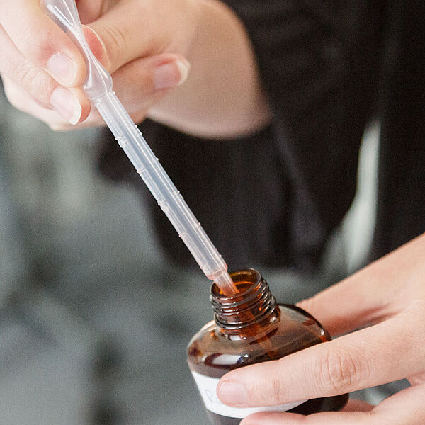 Workshopteilnehmerin entnimmt aus einer braunen Flasche mit einer Pipette eine Flüssigkeit.