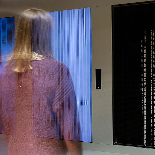 Junge Frau betrachtet ein digitales Kunstwerk in der Ausstellung Neue Medien