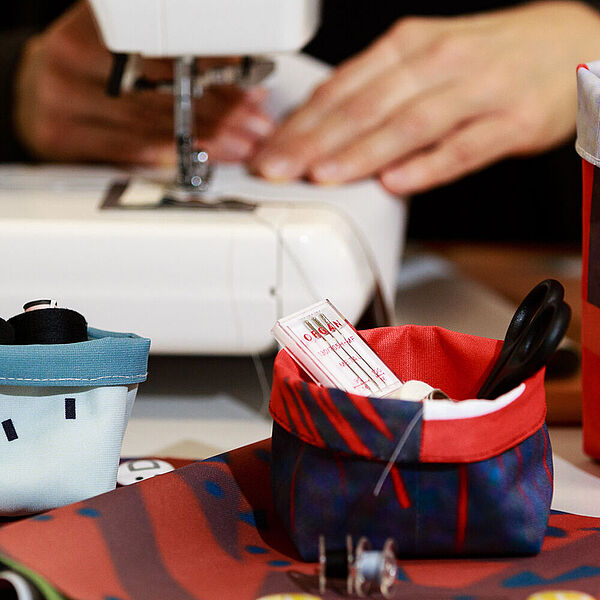 Frau näht Utensilien aus DASA-Bannern im Workshop "Nähen" der DASA