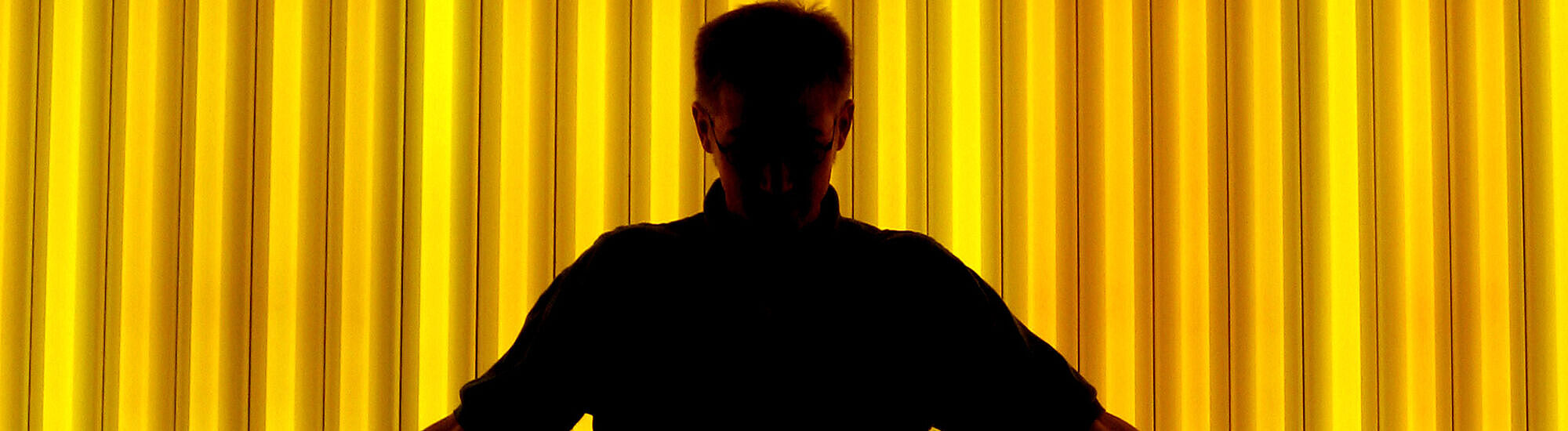 Shilouette eines Mannes vor einer gelbbeleuchteten Wand