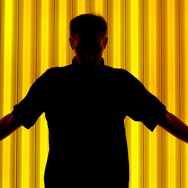 Shilouette eines Mannes vor einer gelbbeleuchteten Wand