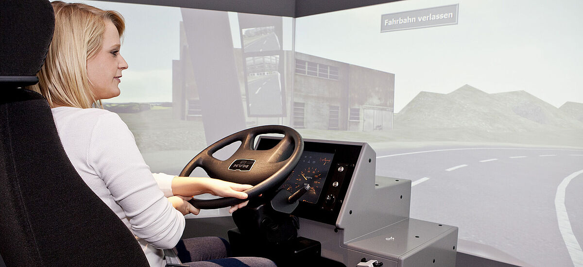 Frau steuert den LKW-Simulator in der DASA
