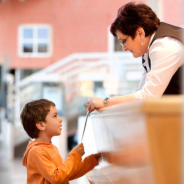 Ein kleiner Junge erhält Informationen an der DASA Infotheke.