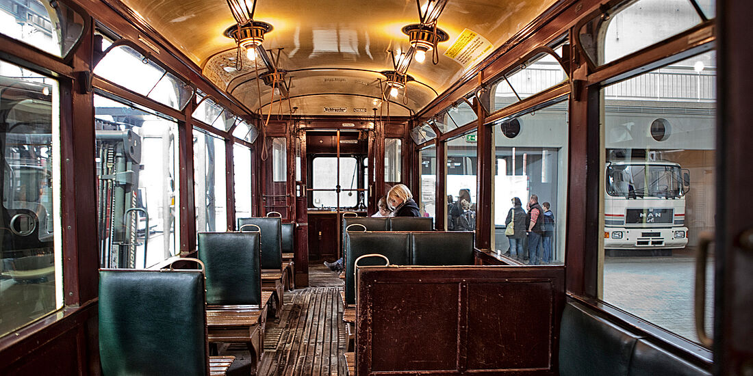 Abteil einer alten Straßenbahn in der eine Besucherin sitzt