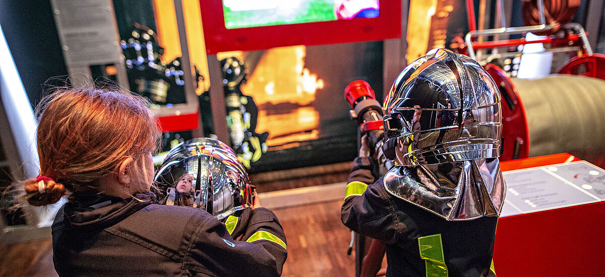 Kinder erkunden ein Spiel in der Ausstellung Feuer.