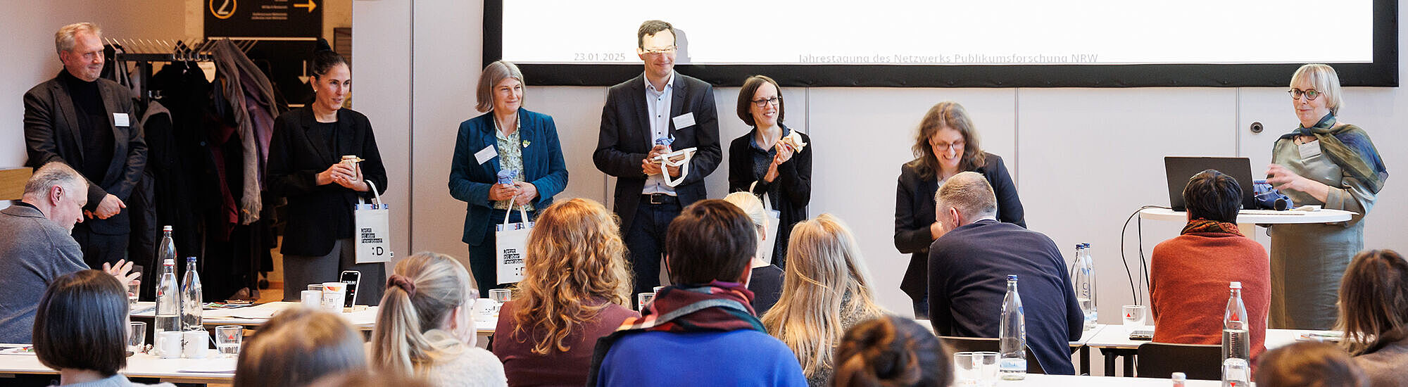 Mitglieder des Netzwerk Publikumsforschung in einem Konferenzraum vor einer Leinwand
