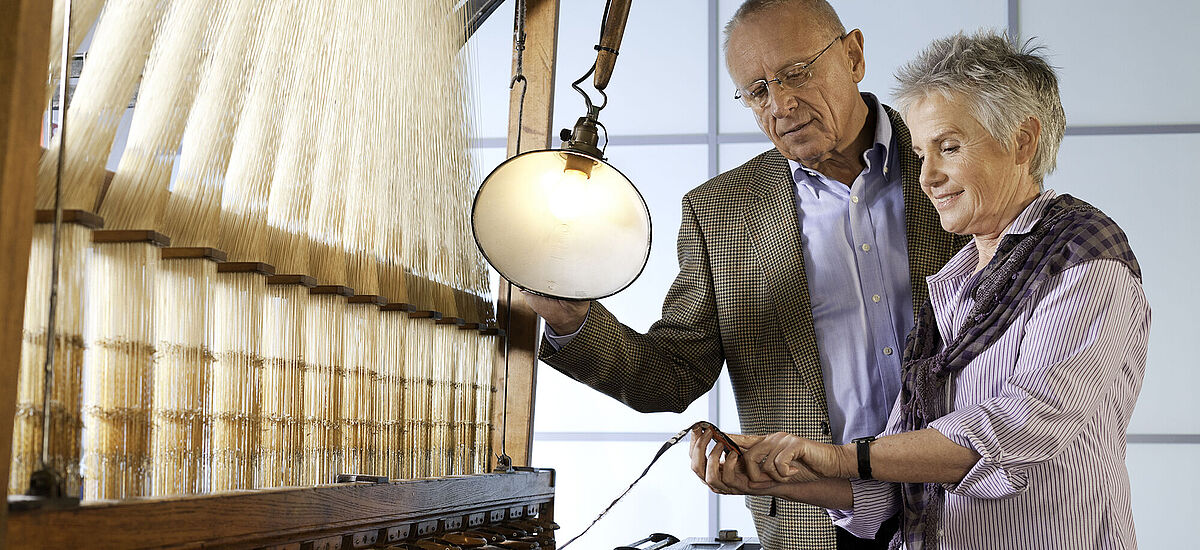 Paar besichtigt den hölzernen Jacquard-Webstuhl in der DASA