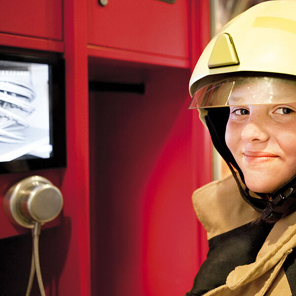 Kind mit Feuerwehrkleidung in der DASA Feuerwehrzone