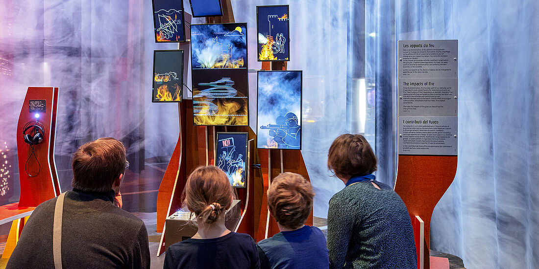 Eine Familie besichtigt eine Multimediastation in der Ausstellung Feuer.