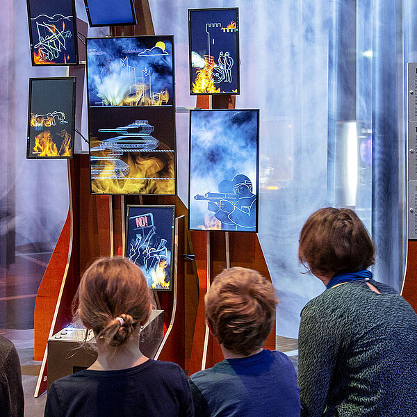 Eine Familie besichtigt eine Multimediastation in der Ausstellung Feuer.