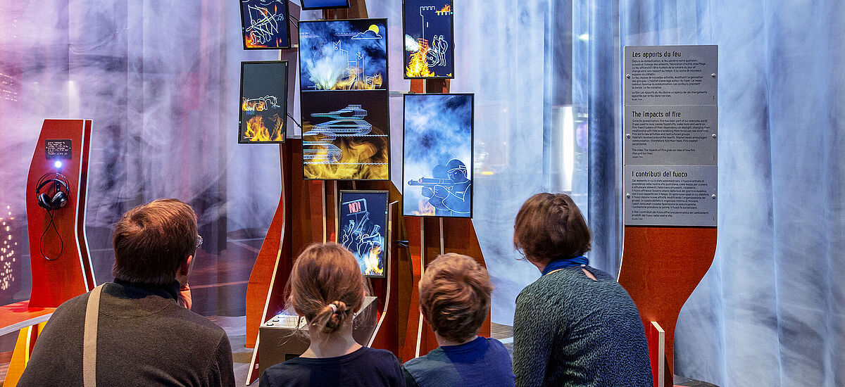 Eine Familie besichtigt eine Multimediastation in der Ausstellung Feuer.