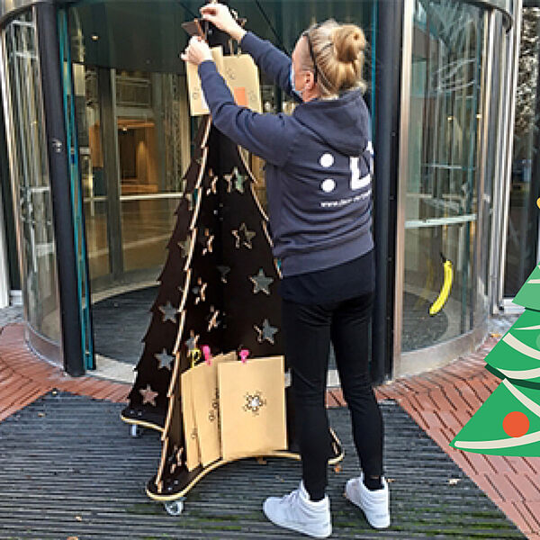 Eine Frau bestückt einen Weihnachtsbaum mit Geschenken
