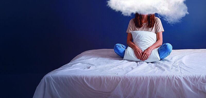 Frau sitzt auf einem zerwühlten Bett. Statt Kopf ist eine Wolke zu sehen. Auf ihr sind Post It für die vielen täglichen Aufgaben, die sie vom Schlafen abhalten.