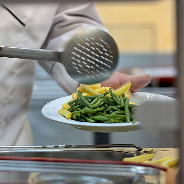 Ein Mann befüllt einen Teller mit Essen