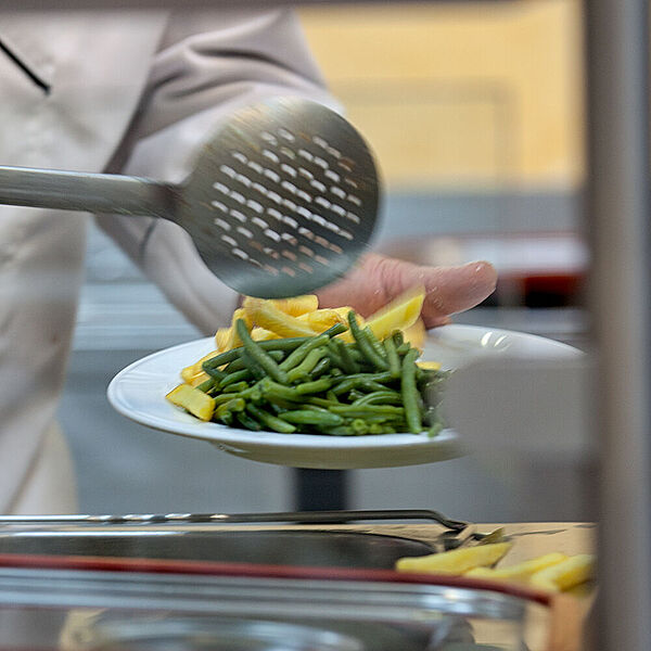 Ein Mann befüllt einen Teller mit Essen