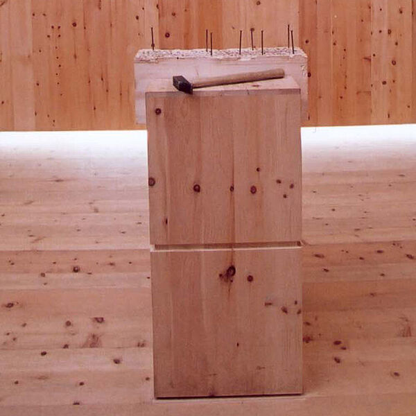 Ausstellungsraum mit Podest in der Mitte auf dem Hammer und Nägel positioniert ist.