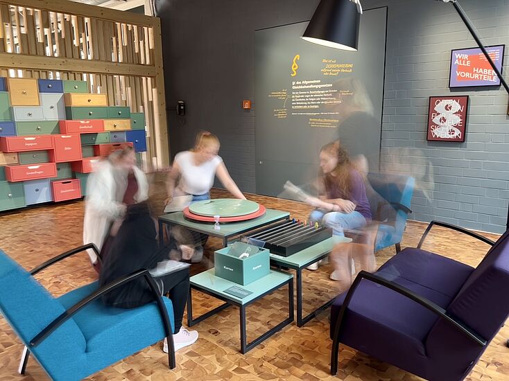 Eine Gruppe Jugendlicher sitzt um einen interaktiven Tisch in der Ausstellung "Dienstleistung" in der DASA und spielt jeweils fiktive Biografien nach.