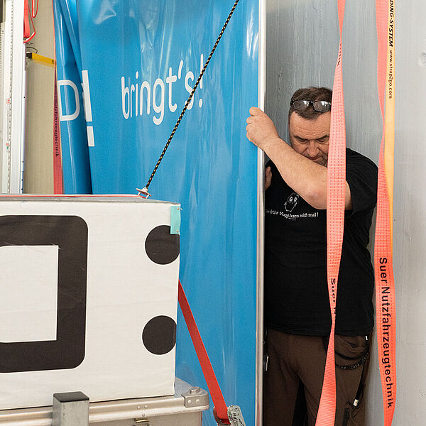 Ein Vorführtechniker zeigt in der DASA, wie Ladung im Innern eines LKW sicher verstaut werden kann.