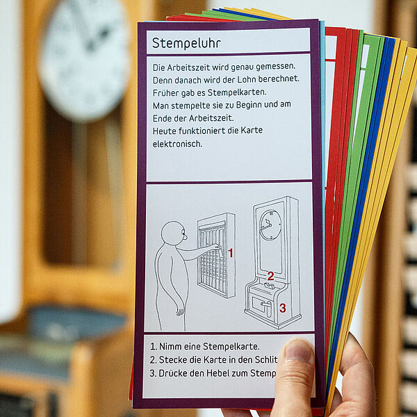 Mädchen hält DASA Entdeckerkarten vor der Stempeluhr hoch