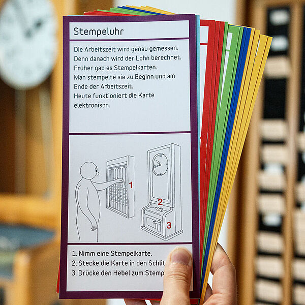 Mädchen hält DASA Entdeckerkarten vor der Stempeluhr hoch