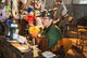 Eine Frau in viktorianisch anmutendem Kostüm sitzt an einem Stand mit Acceossires aus der Welt von Steampunks 