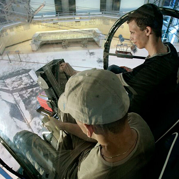 Jugendliche sitzen in einem Hunschrauber in der Energiehalle der DASA
