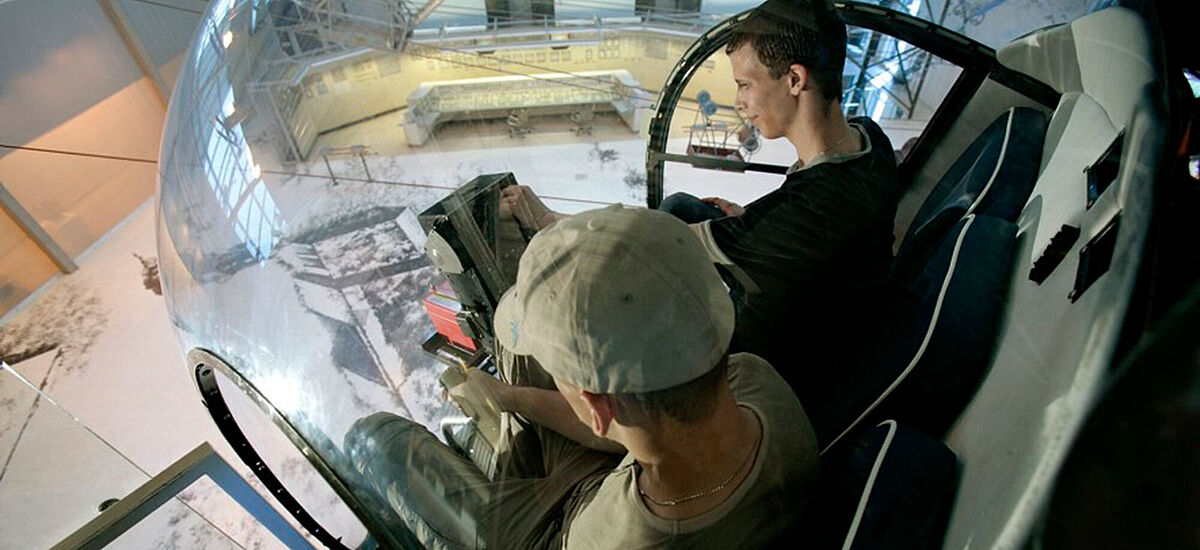 Jugendliche sitzen in einem Hunschrauber in der Energiehalle der DASA