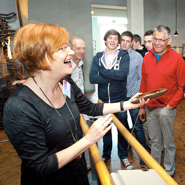 Eine Moderatorin führt eine Gruppe Besucher durch die Weberei in der DASA.