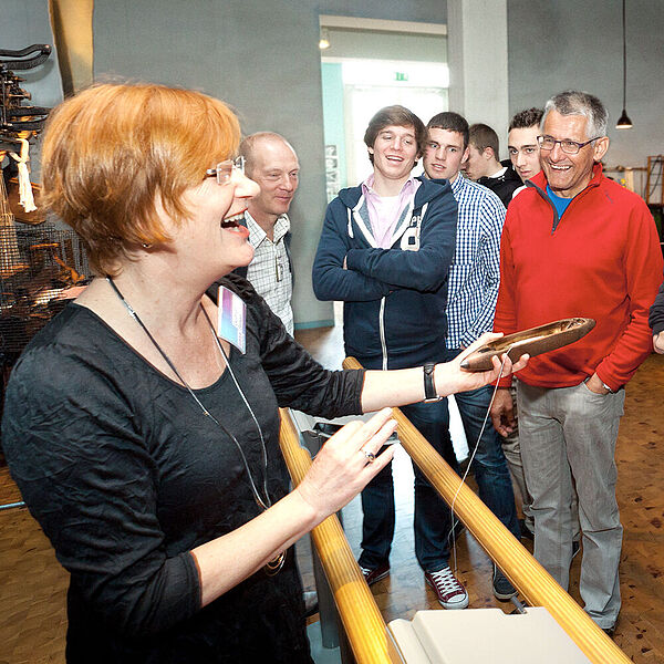 Eine Moderatorin führt eine Gruppe Besucher durch die Weberei in der DASA.