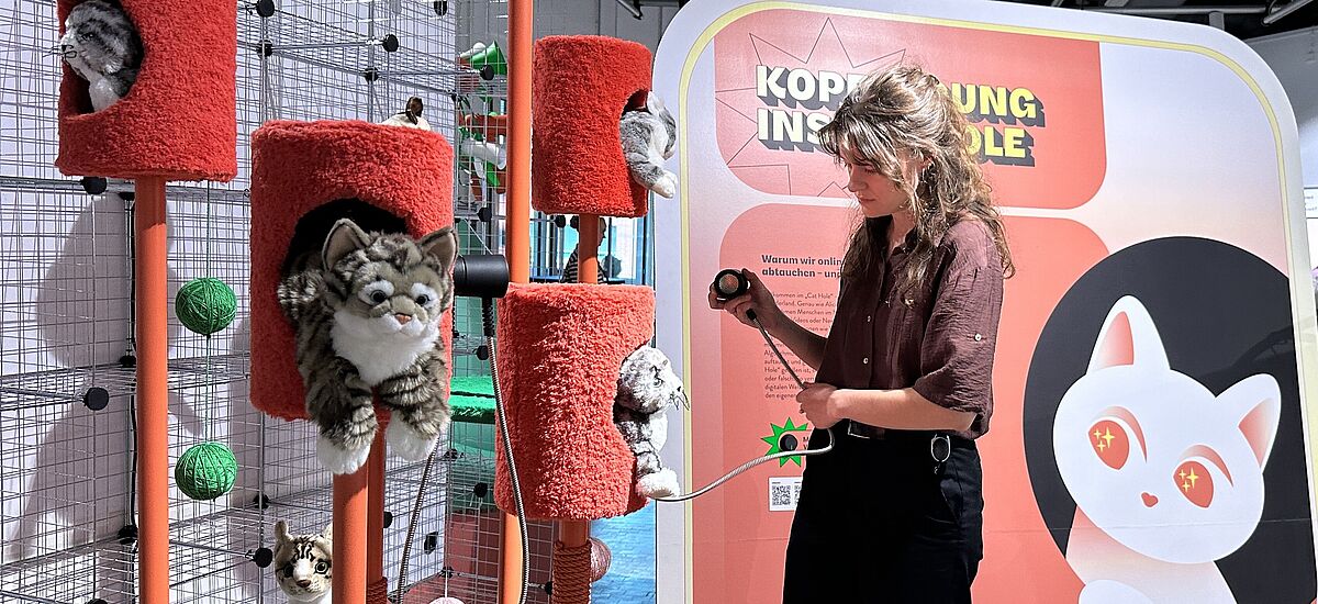 Kratzbäume Besucherin vor einem Kratzbaum für Katzen in der Ausstellung "Alles im Angebot".