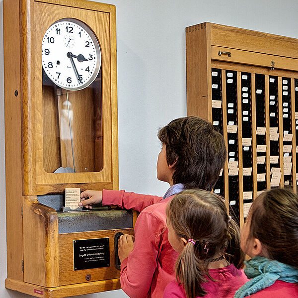 Kinder vor der Stempeluhr zur Zeiterfassung in der DASA