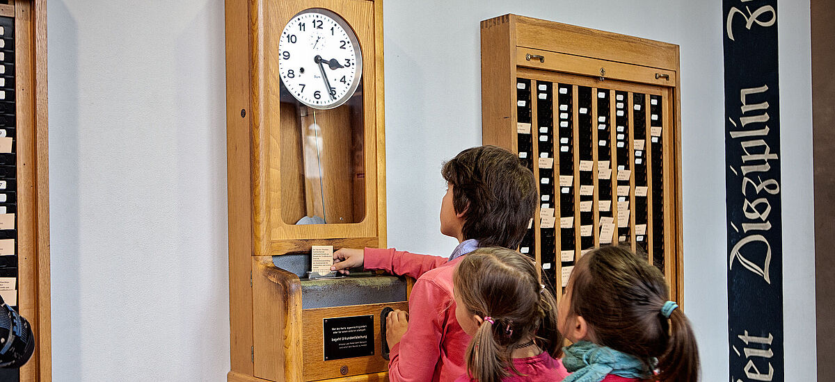 Kinder vor der Stempeluhr zur Zeiterfassung in der DASA