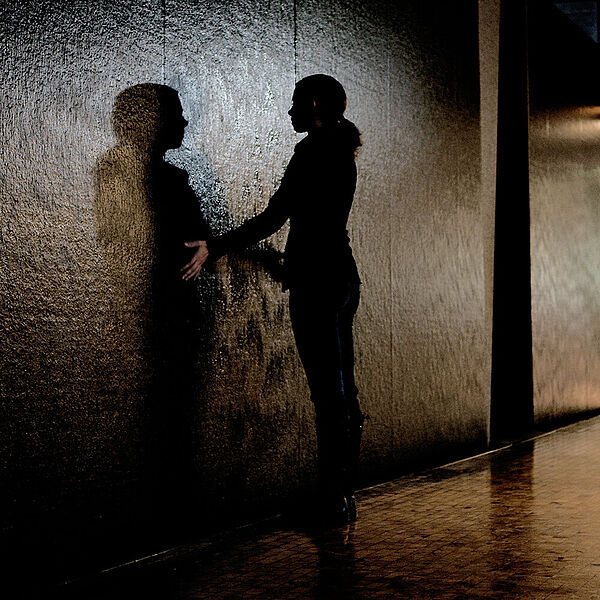 Junge Besucherin hält beide Hände an eine Wand an der Wasser herunter fliesst.