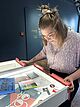 Frau schaut sich in der Ausstellung Dienstleistung in der DASA eine herausziebare Schublade zum Thema Vorurteile an.