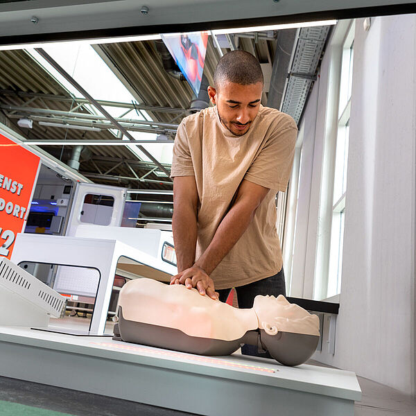 Junger Mann probiert Herzdruckmassage an einer Übungspuppe in der Ausstellung "Heilen und Pflegen".