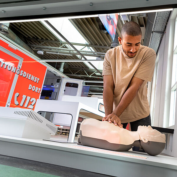 Junger Mann probiert Herzdruckmassage an einer Übungspuppe in der Ausstellung "Heilen und Pflegen".